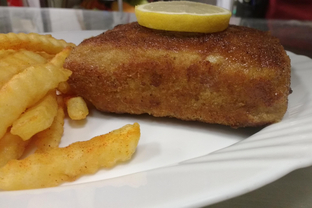 Ein Cordon Bleu als Packerl mit Zitronenscheibe und Pommes